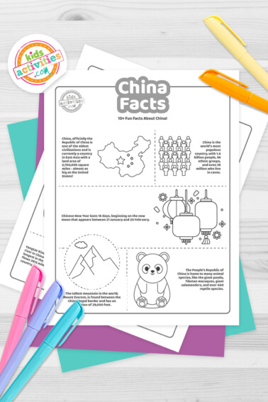Black and white coloring pages with China facts lying on top of a blue-green and purple sheets with multicolored markers on a light grey background.