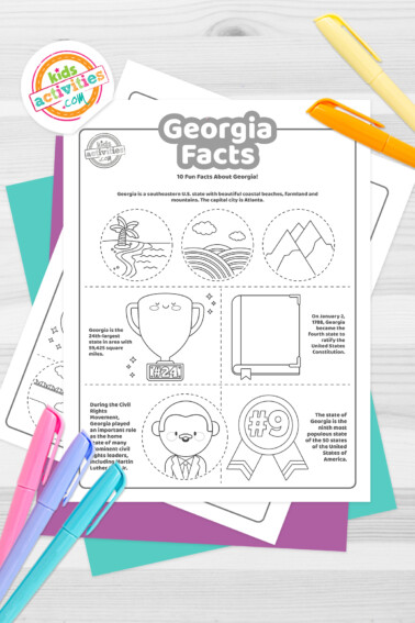 Black and white coloring pages with Georgia facts lying on top of blue-green and purple sheets with assorted crayons on a light grey background.