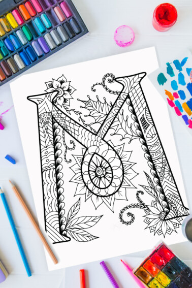 Zentangle alphabet coloring pages - letter m zentangle design on background of paint, colored pencils and art supplies
