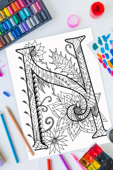 Zentangle alphabet coloring pages - letter n zentangle design on background of paint, colored pencils and art supplies