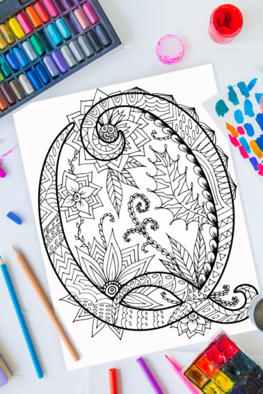 Zentangle alphabet coloring pages - letter q zentangle design on background of paint, colored pencils and art supplies