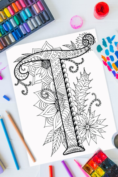Zentangle alphabet coloring pages - letter t zentangle design on background of paint, colored pencils and art supplies
