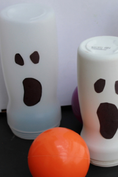 Home made ghost bowling pins are about to be hit by an orange ball that kinda looks like a pumpkin